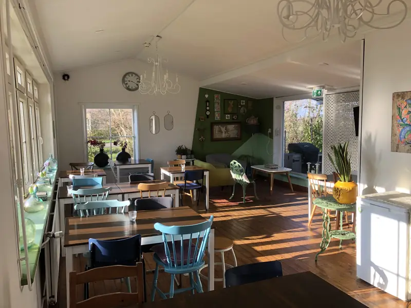 De lichte eetzaal met houten vloer en blauwe stoelen