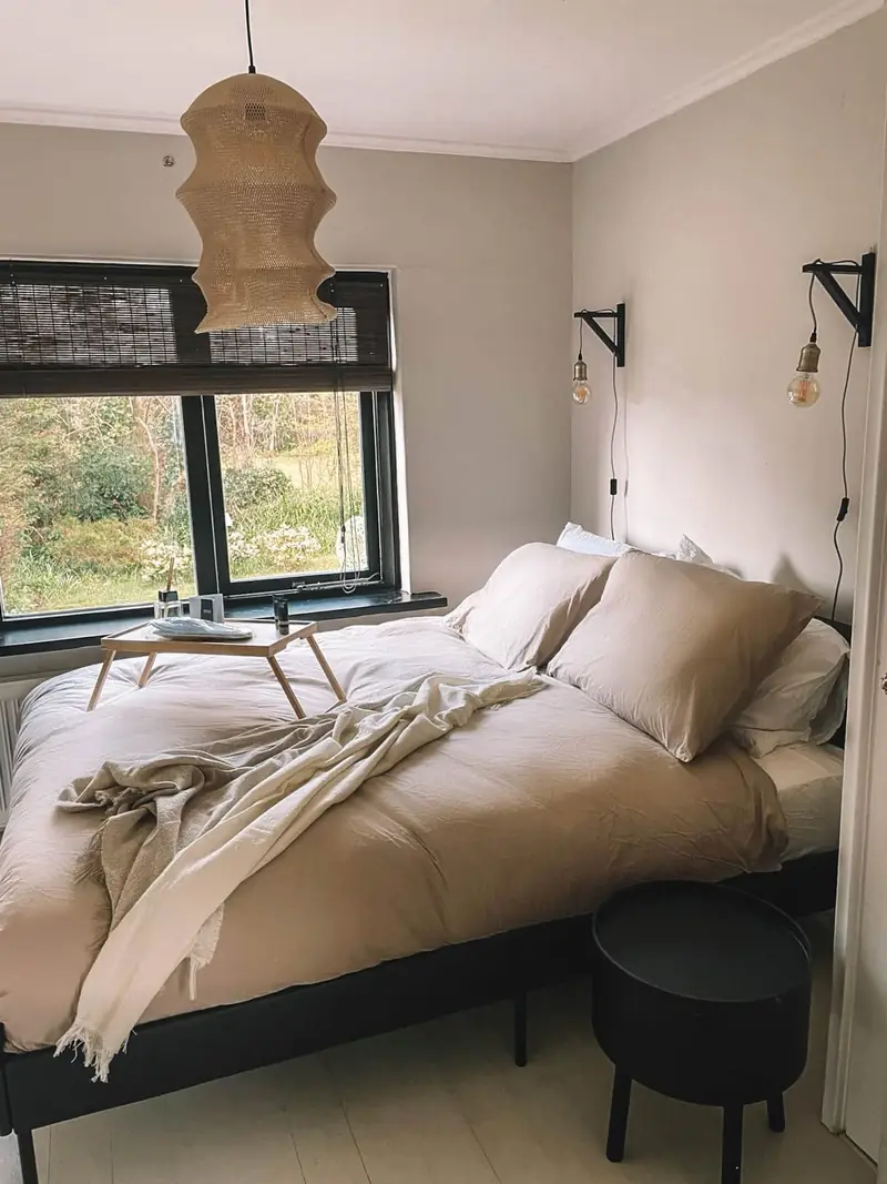 Tuinkamer met een tweepersoonsbed en een lamp van rotan